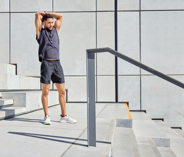 Stay focused and keep grinding. Shot of a sporty young man listening to music and stretching his arms while exercising outdoors.