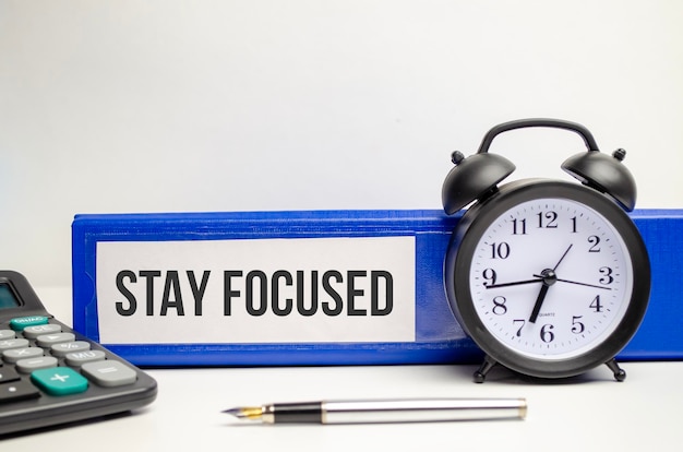 Stay Focused word on paper folder and alarm clock and calculator