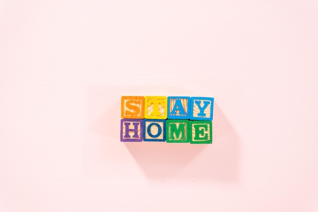 STAY HOME sign out of kids' alphabet blocks on a pink background