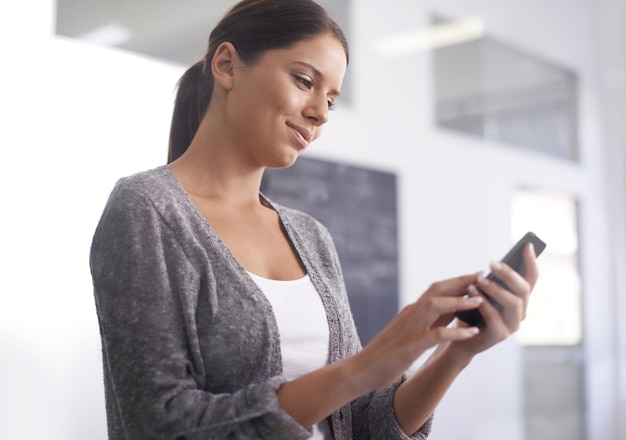 Staying in touch every minute of the day A beautiful young woman using her smartphone at the office