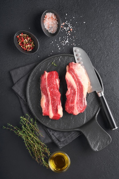 Steak beef Raw steak New York with rosemary and spices on old iron plate on old dark stone background Top view Mock up