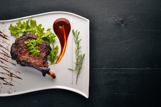 Photo steak on a bone with tomatoes and a hazelnut steak fiorentino on a wooden background free space for your text top view