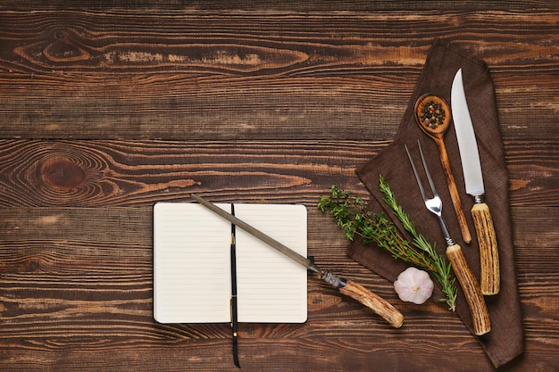 Steak fork knife and sharpener on wooden table next to notebook