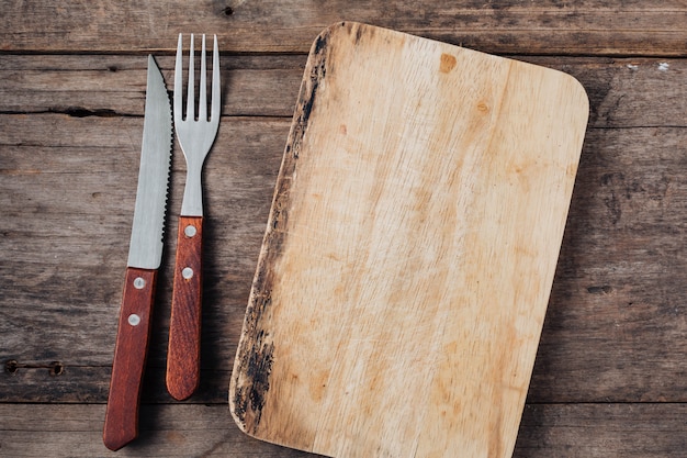 Steak fork and knife on wooden background