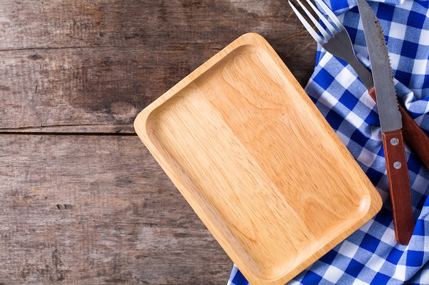 Steak knife and a fork with blue table cloth on wooden background