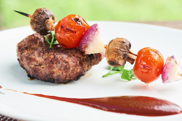 Steak and vegetables on skewers, served on a white plate