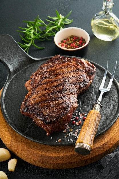 Steaks Grilled New York Steak with spices rosemary and pepper on black marble board on gray background Top view Mock up