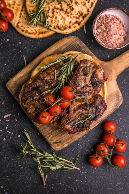 Steaks Sliced grilled meat steak New York or Ribeye with spices rosemary and pepper on black board Top view