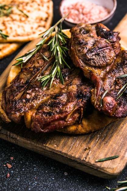 Steaks Sliced grilled meat steak New York or Ribeye with spices rosemary and pepper on black board Top view