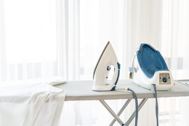 Steam iron standing on ironing board near window with copy space