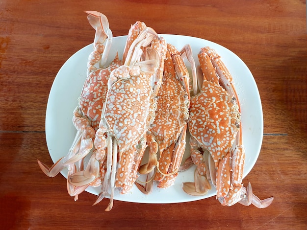 Steamed blue crab in the plate on wooden background.