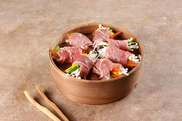 Steamed Bulgogi Rolls or Beef Rolls Stuffed with Sweet Pepper and Enoki Mushroom in Bamboo Steamer.