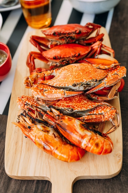 Steamed Giant Mud Crabs, Steamed Flower Crabs and Grilled Shrimps (Prawns) in wooden chopping board. 