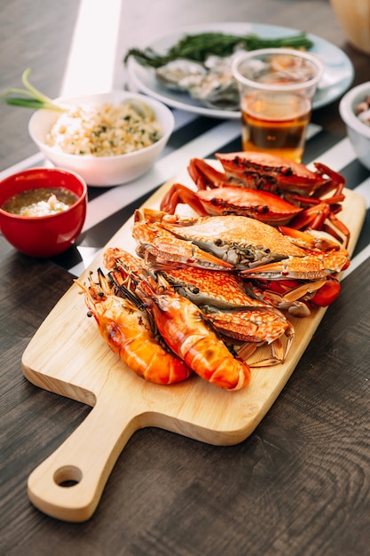 Steamed Giant Mud Crabs, Steamed Flower Crabs and Grilled Shrimps (Prawns) in wooden chopping board. 