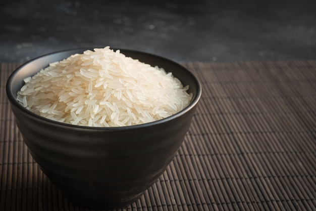 Steamed rice in bowl on black background. Copy space.