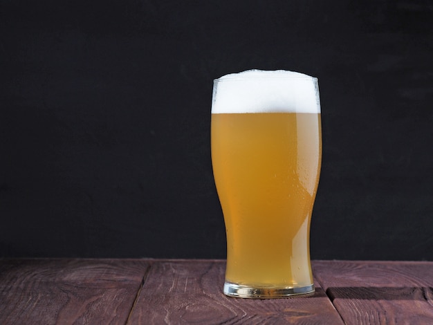 A steaming glass of unfiltered beer with a frothy cap on a wooden table