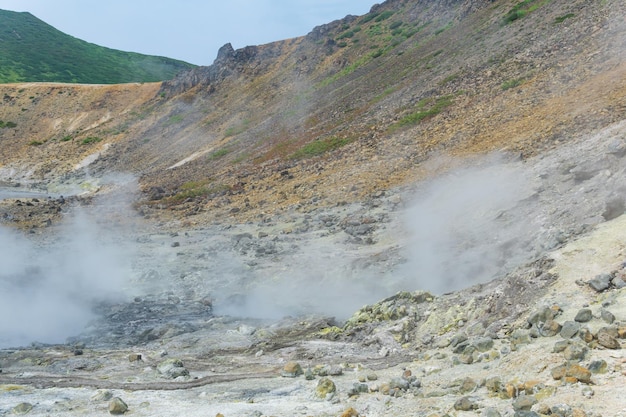 Steaming hydrothermal outlet on the shore of the hot lake in the caldera of the Golovnin volcano on the island of Kunashir