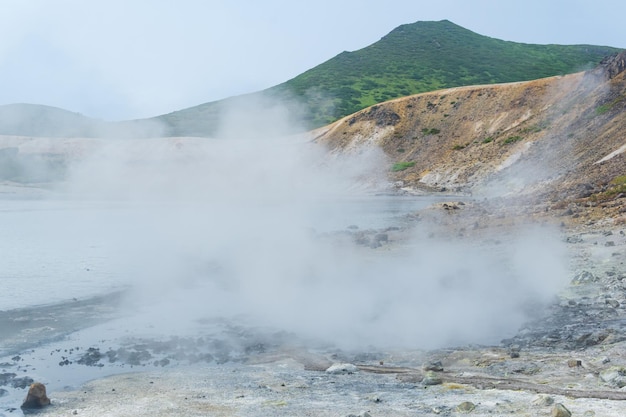 Steaming hydrothermal outlet on the shore of the hot lake in the caldera of the Golovnin volcano on the island of Kunashir