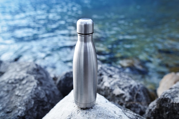 Steel eco thermo water bottle on the background of the lake