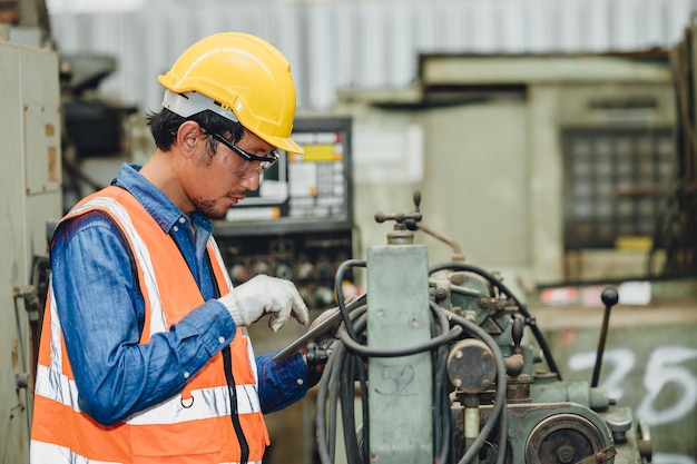 Steel factory staff worker Asian man work in a heavy industrial machine with safety engineer uniform