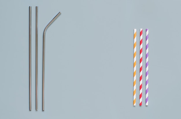 Steel and paper drinking straws on grey background top view with copy space