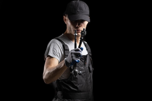 steering rods in the hand of an auto mechanic, craftsman on a dark background. Car steering repair c