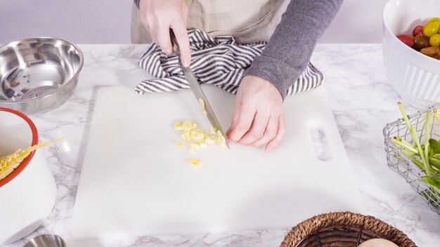 Step by step. Cutting vegetables on a white cutting board to make a one-pot pasta recipe.