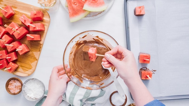 Step by step. Dipping watermelon cubes into melted chocolate and garnishing with sea salt and almonds.