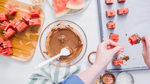 Step by step. Dipping watermelon cubes into melted chocolate and garnishing with sea salt and almonds.