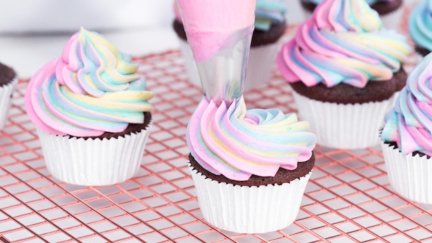 Step by step. Frosting unicorn chocolate cupcakes with rainbow color buttercream frosting.