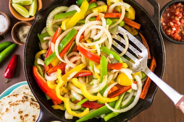 Step by step. Frying fresh vegetables in large cast iron pan for steak fajitas.