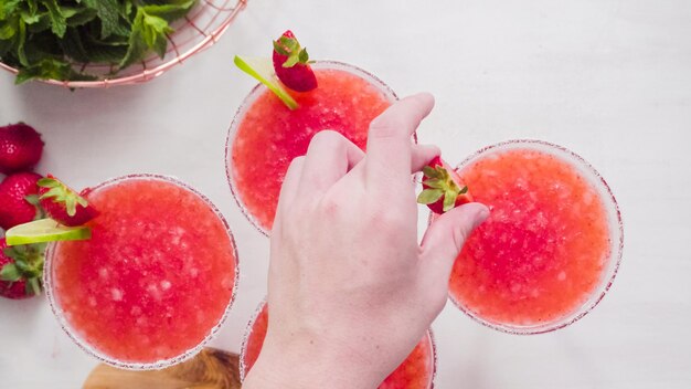 Step by step. Garnishing strawberry margarita with fresh lime and strawberries.