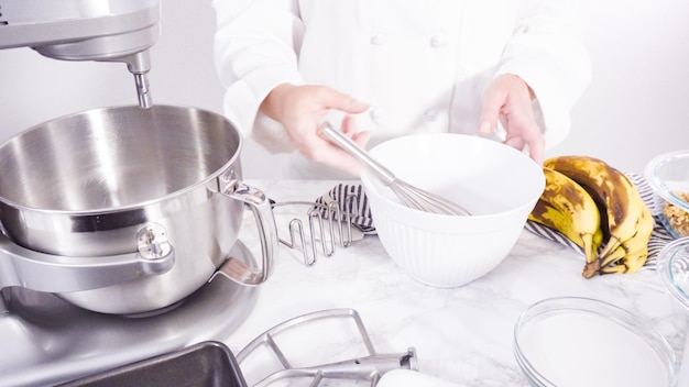 Step by step. Mixing ingredients together into a metal mixing bowl to bake banana bread.