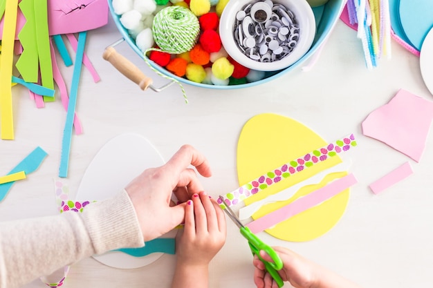 Step by step. Mother and daughter decorating paper Easter eggs.