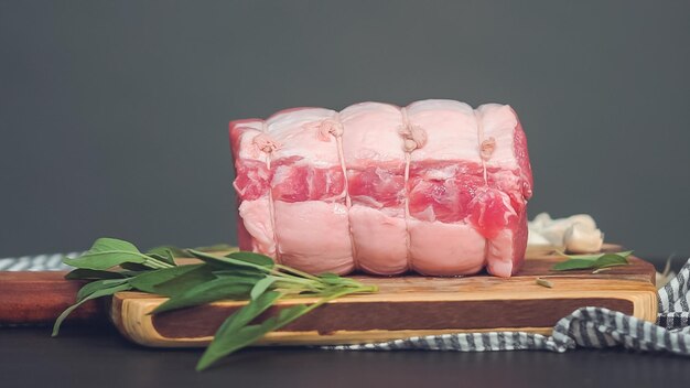 Step by step. Raw boneless pork roast on wood cutting board with spices.