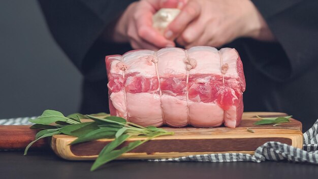 Step by step. Raw boneless pork roast on wood cutting board with spices.