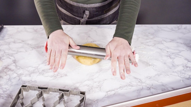 Step by step. Rolling out sugar cookie dough to bake Christmas cookies.