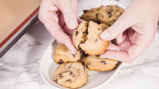 Step by step. Scooping homemade chocolate chip cookies with metal dough scoop to the baking sheet.