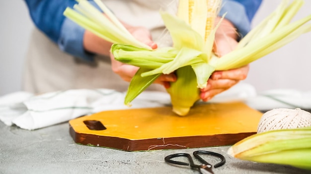 Step by step. Shucking organic corn to make Mexican corn on the cob Elote.