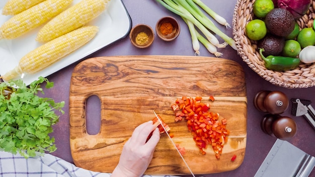 Step by step. Slicing red bell pepper on a wood cutting board.