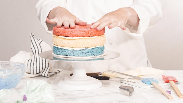 Step by step. Stacking cake layers to create the round three-layer vanilla cake.