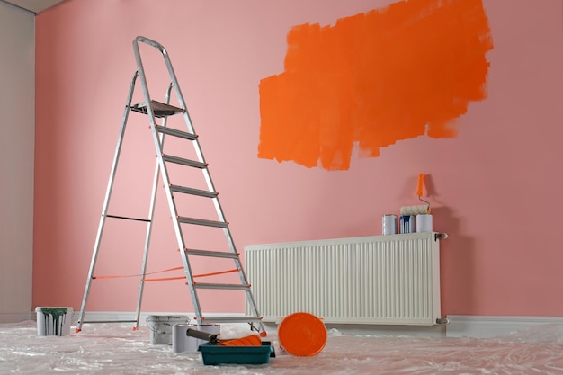 Photo stepladder and painting tools near wall in empty room