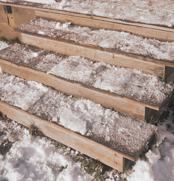 The steps of wooden stairs are covered with snow during a snowfall Descent to the yard of the house Cold day in the village