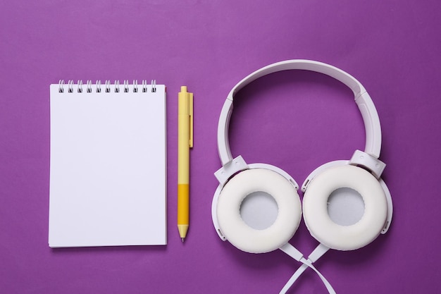 Stereo headphones and blank notebook for copy space on purple background Fitness concept Training plan