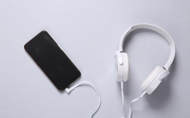 Stereo headphones connected to smartphone on gray background