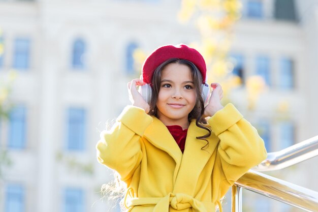 Stereo sound Child girl autumn outfit enjoying music Awesome sound Girl kid with headphones urban background Little girl listening music enjoy favorite song excellent sound Good vibes only