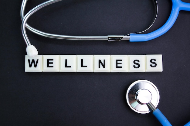 stethoscope and alphabet letters with the word wellness health and medical concepts