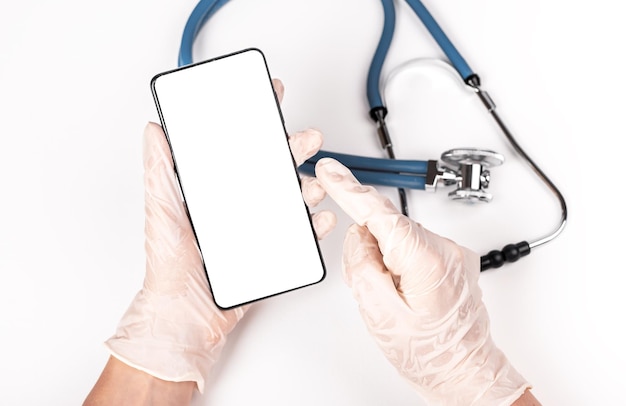 Stethoscope and doctor hands holding phone mockup for online medical consultation communication with patient or using health tracker app in smartphone