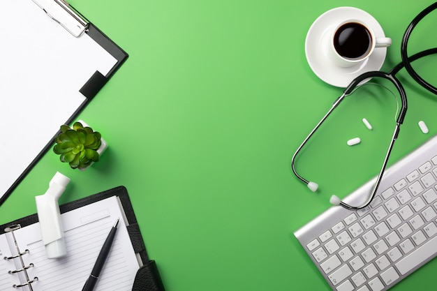 Photo stethoscope in doctors desk with cup coffee, keyboard and pills