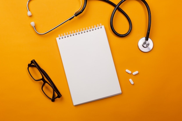 Stethoscope in doctors desk with notebook and pills